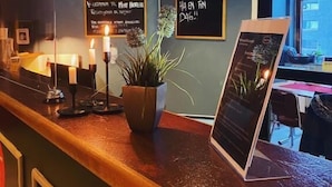 A hotel reception area with a wooden counter, candles, a potted plant, and a chalkboard with text. - Mitt hotell apartments (Moss)