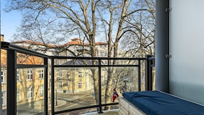 A balcony with a bed, a view of buildings, and a flag. - Mitt hotell apartments (Moss)
