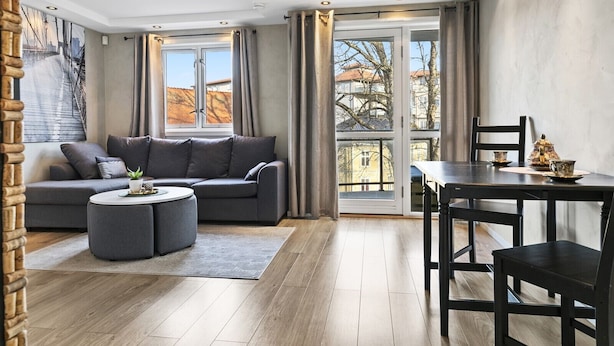 A modern living room with a grey sofa, a round coffee table, and a dining table with chairs. - Mitt hotell apartments (Moss)