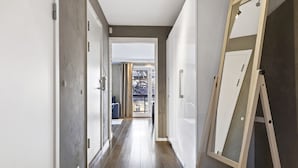 A hallway with a wooden floor, white walls, and a large mirror leaning against the wall. - Mitt hotell apartments (Moss)