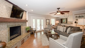 A living room with a fireplace, a television, a ceiling fan, and a couch.