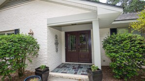 A house with a white exterior, a dark brown front door, and a covered porch area.