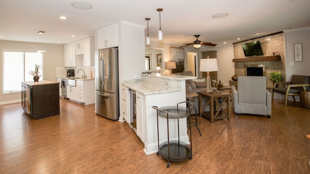 A spacious kitchen with white cabinets, a stainless steel refrigerator, and a marble island.