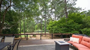 An outdoor deck with a wooden floor, a sofa, a table, and chairs.