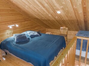 Une chambre dans une cabane en bois, avec un lit superposé, une petite table et une chaise.