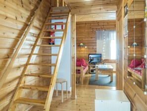 Ein Holzinnenraum mit Schlafzimmer im oberen Bereich, einer Essecke und einem Wohnzimmer mit Fernseher.
