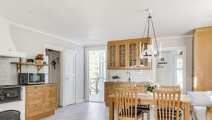 Une cuisine moderne avec des meubles en bois, une table à manger avec des chaises et un luminaire suspendu.