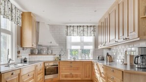 Une cuisine moderne avec des meubles en bois, un four encastré et une fenêtre avec des rideaux.