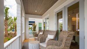 A covered porch with wicker furniture and a view of the outside. - Over the Moon, 30A Home, Golf Cart, Elevator, Pool (Santa Rosa Beach)
