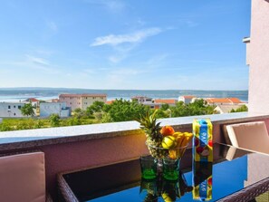 A balcony with a table, a vase with fruits, and a bottle of water. - Apartment Ika by Interhome (Maslenica)