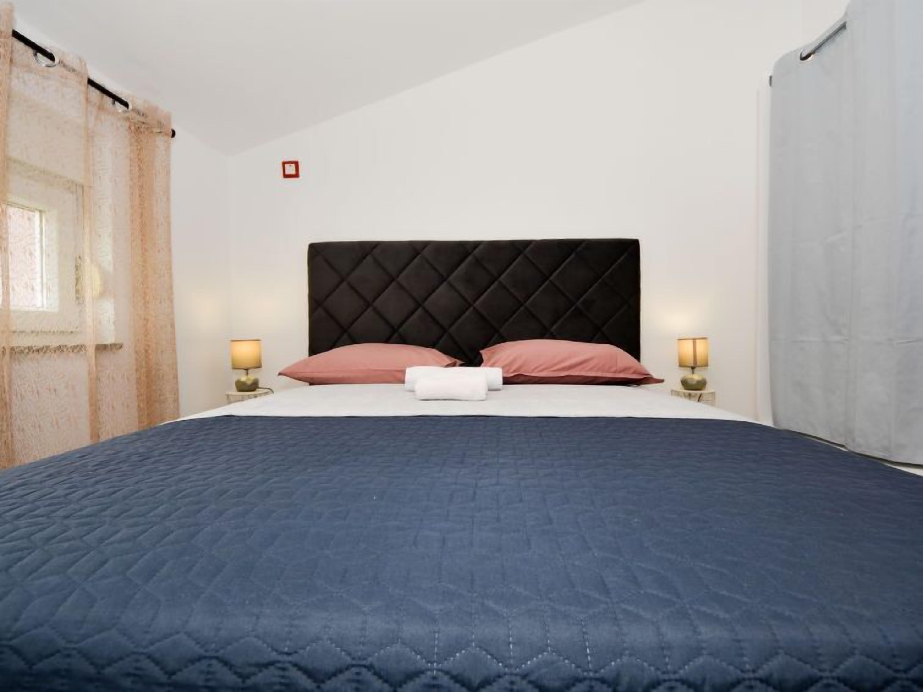 A neatly arranged bedroom with a large bed, two bedside lamps, and a headboard.