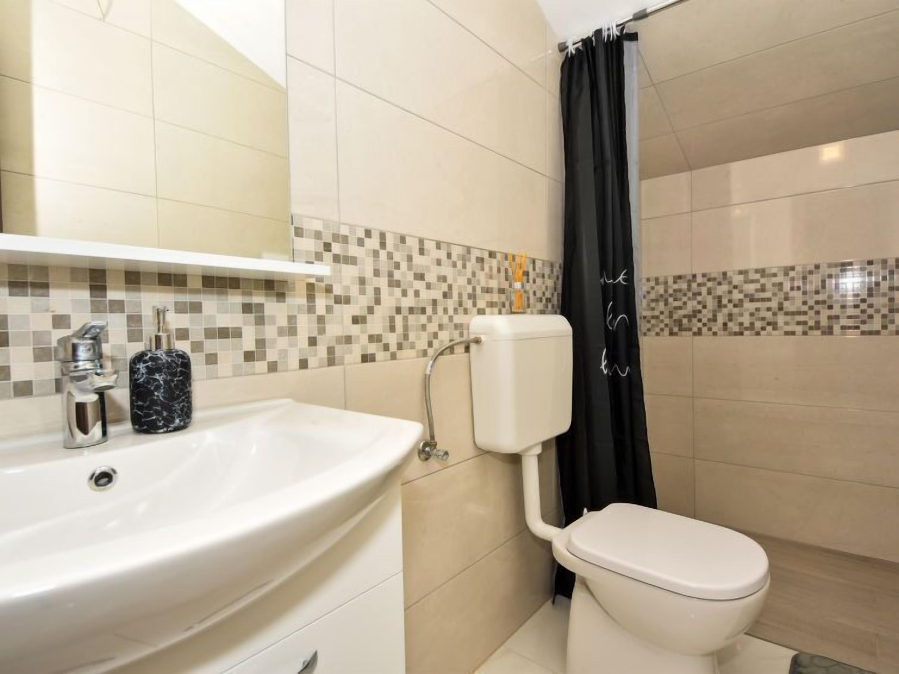 A bathroom with a white sink, a toilet, and a shower curtain.