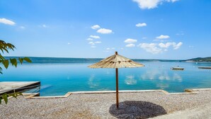 Une plage avec un parasol en chaume et un banc en bois.