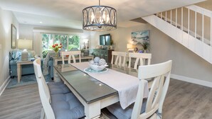 Een eetruimte met een tafel voor vier personen, een kroonluchter en een trap naar een hoger niveau.