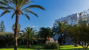 A well-maintained garden with palm trees and a building with white walls and blue accents. - Cala Blanca Denia by Interhome (Dénia)