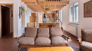 A spacious living area with a wooden staircase, a sofa, and a dining table.