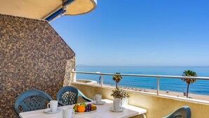 Un balcon avec une table préparée pour le petit-déjeuner, donnant sur une plage.