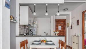 Un coin repas avec une table dressée pour quatre personnes, une cuisine en arrière-plan et une porte en bois.