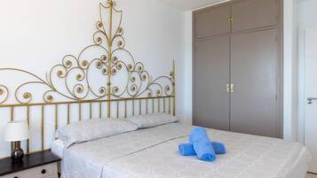 Un dormitorio con cama, mesita de noche, armario y un cabecero decorativo de metal.