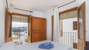 Ein Hotelzimmer mit Bett, Balkon und Blick sowie einem Holzschrank.