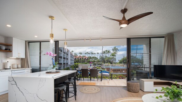 A modern kitchen with a marble island, bar stools, and pendant lighting. - Maui Parkshore 204 2BR across Kamaole III Beach w/ ocean views, summer deal (Kihei)