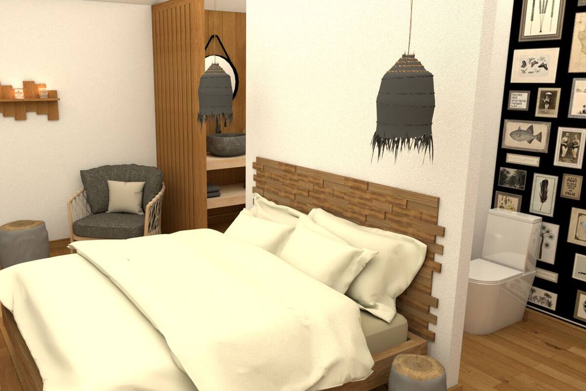 Ein Schlafzimmer mit einem hölzernen Bett, einem Sessel, einem kleinen Hocker, einer Pendelleuchte und einer Wand mit gerahmten Bildern.