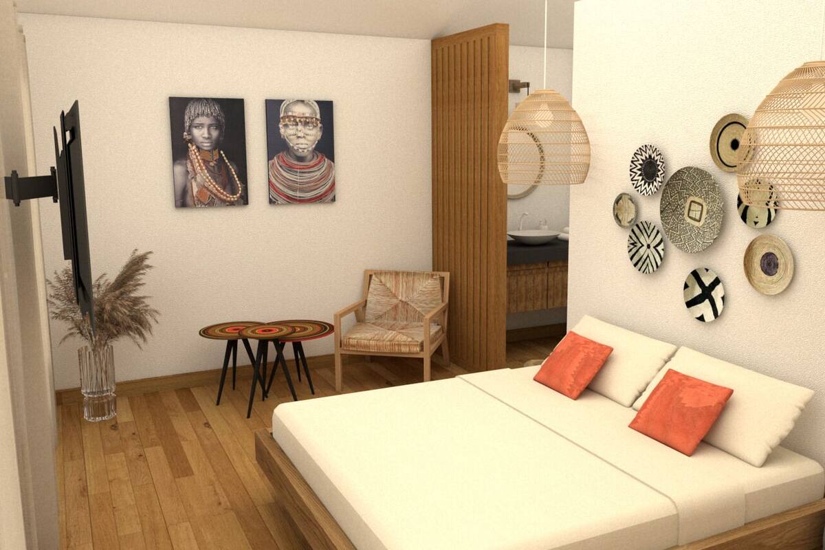 Ein modernes Schlafzimmer mit einem weißen Bett, zwei roten Kissen, einem Sessel, einem kleinen runden Tisch und Wandbildern.