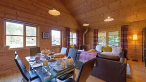 L’intérieur d’un chalet accueillant, avec une table à manger dressée pour le repas, un canapé agrémenté de coussins et une cheminée.