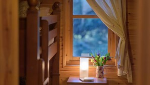 A wooden cabin interior with a window, a candle, and a floral vase on a table. - Cosy, comfortable lodge sleeps 6 guests  in 3 bedrooms. Pet friendly! (Banchory)