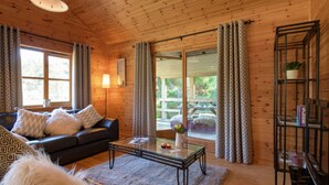 A cozy cabin interior with a leather sofa, a glass coffee table, and a bookshelf. - Cosy, comfortable lodge sleeps 6 guests  in 3 bedrooms. Pet friendly! (Banchory)