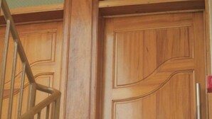 Una puerta de madera con un picaporte metálico y una barandilla a su lado.