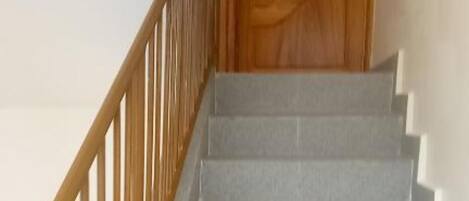 A staircase with a wooden handrail and a closed wooden door at the top.