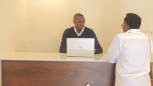 Mostrador de recepción con una computadora portátil y una persona detrás.