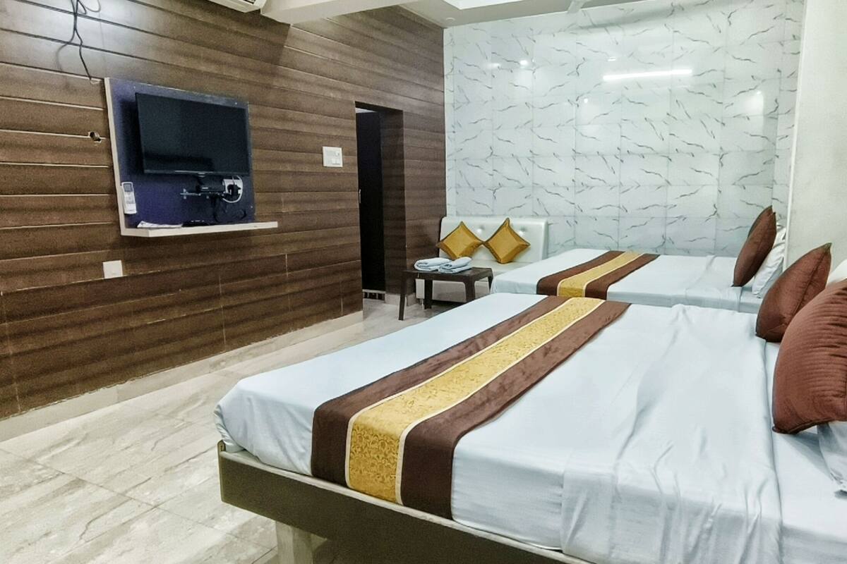 Habitación de hotel con dos camas, un televisor en la pared y paredes con diseño de mármol.