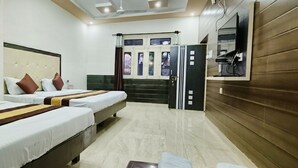 A hotel room with three beds, a television, and a wardrobe. - Hotel Prabhat Palace (Kota)