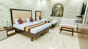 A hotel room with two beds, a small desk, a mirror, a TV, and a wall-mounted artwork of a tiger. - Hotel Prabhat Palace (Kota)
