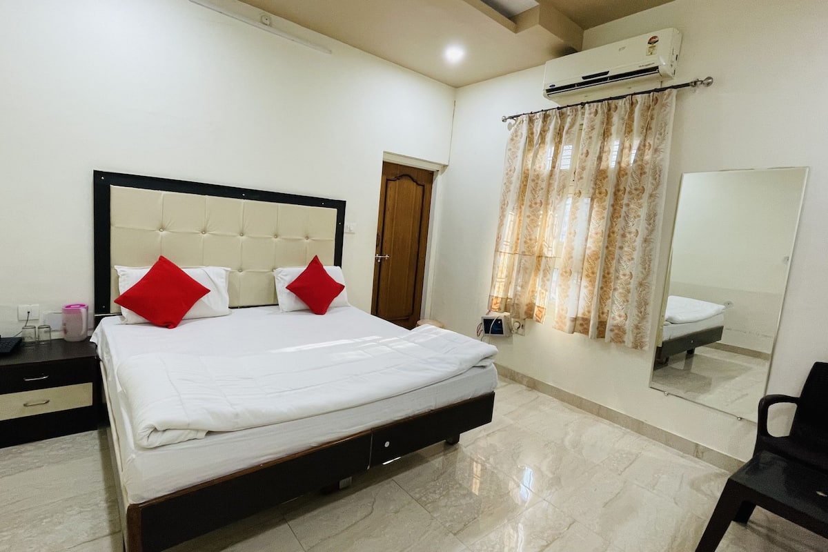 Una habitación de hotel con cama, mesita de noche, espejo y aire acondicionado.