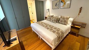 A bedroom with a large bed, a wardrobe, a desk, and a TV. - Condo on the beach (Collectivité de Saint-Martin)