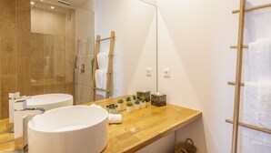 A modern bathroom with a wooden vanity, a large mirror, and a glass shower enclosure. - Condo on the beach (Collectivité de Saint-Martin)