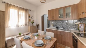 Una cucina moderna con mobili in legno, zoccolo piastrellato e zona pranzo con tavolo imbandito per quattro persone.