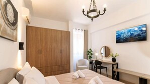 Una camera d'albergo con un letto, una scrivania, una sedia, un armadio e una TV appesa al muro.