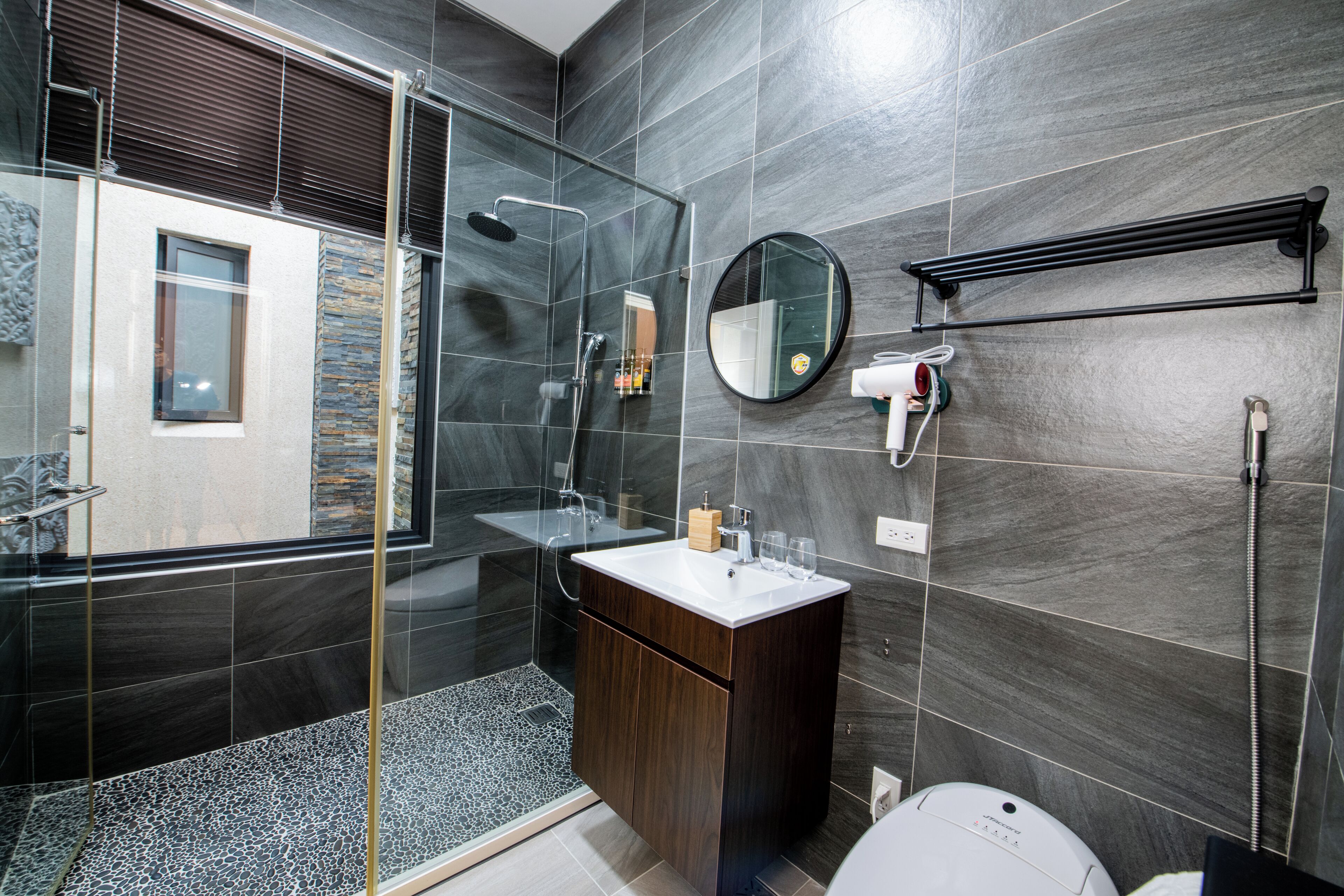 A modern bathroom with a glass-enclosed shower, a vanity with a mirror, and a towel rack.