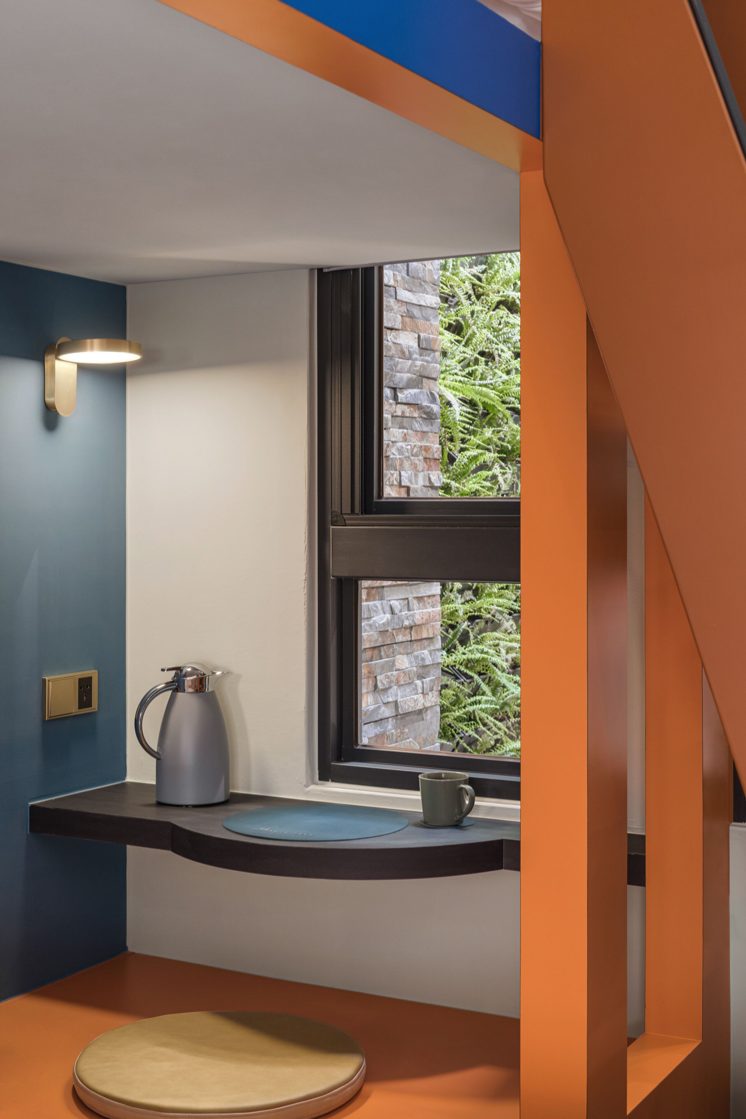 Un baño moderno con ventana, hervidor y taza sobre el mostrador.