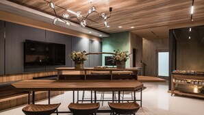 Een moderne keuken met een houten eiland, barstoelen en een grote flatscreen-televisie.