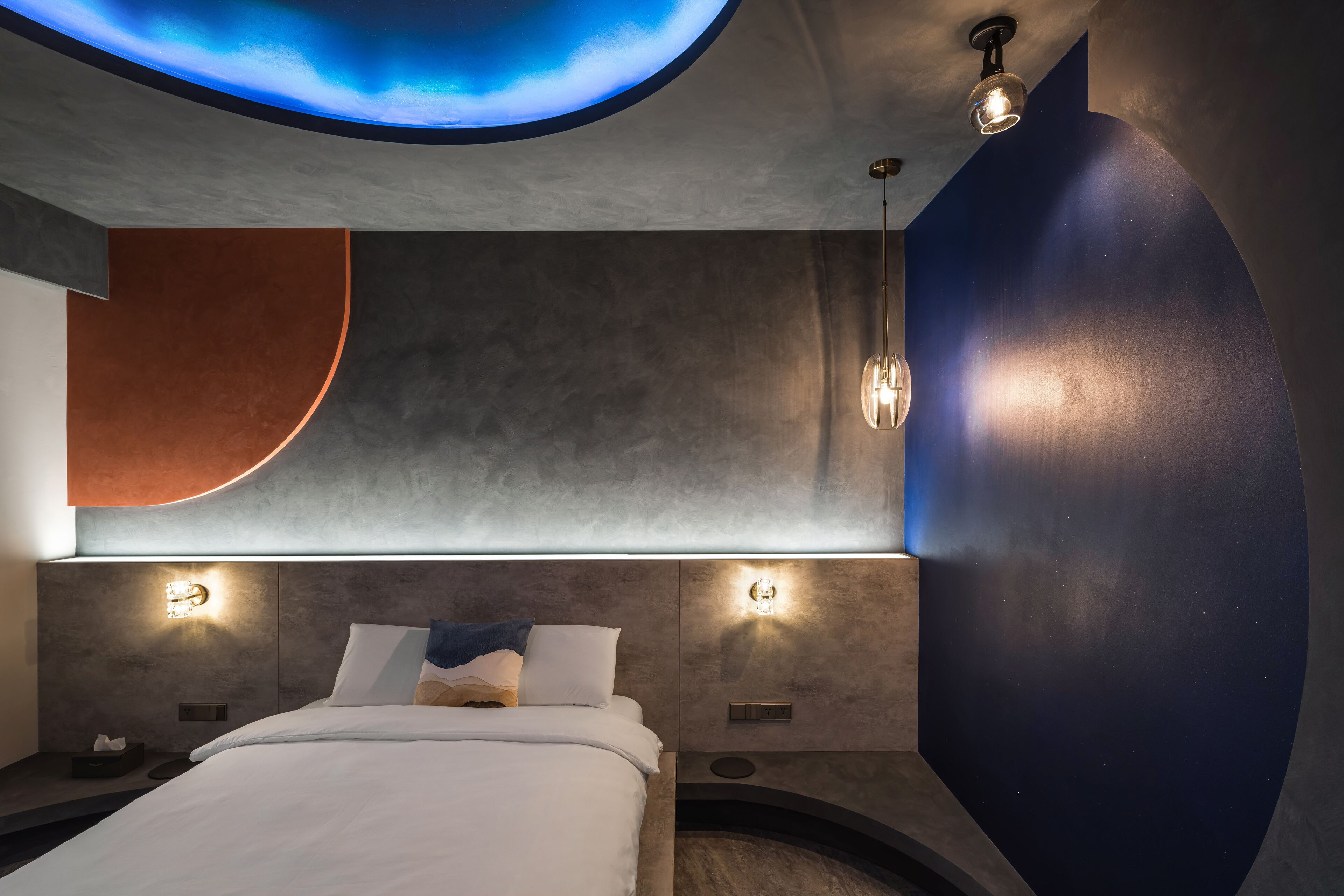 A modern hotel room with a curved ceiling, recessed lighting, and a large bed with white linens.