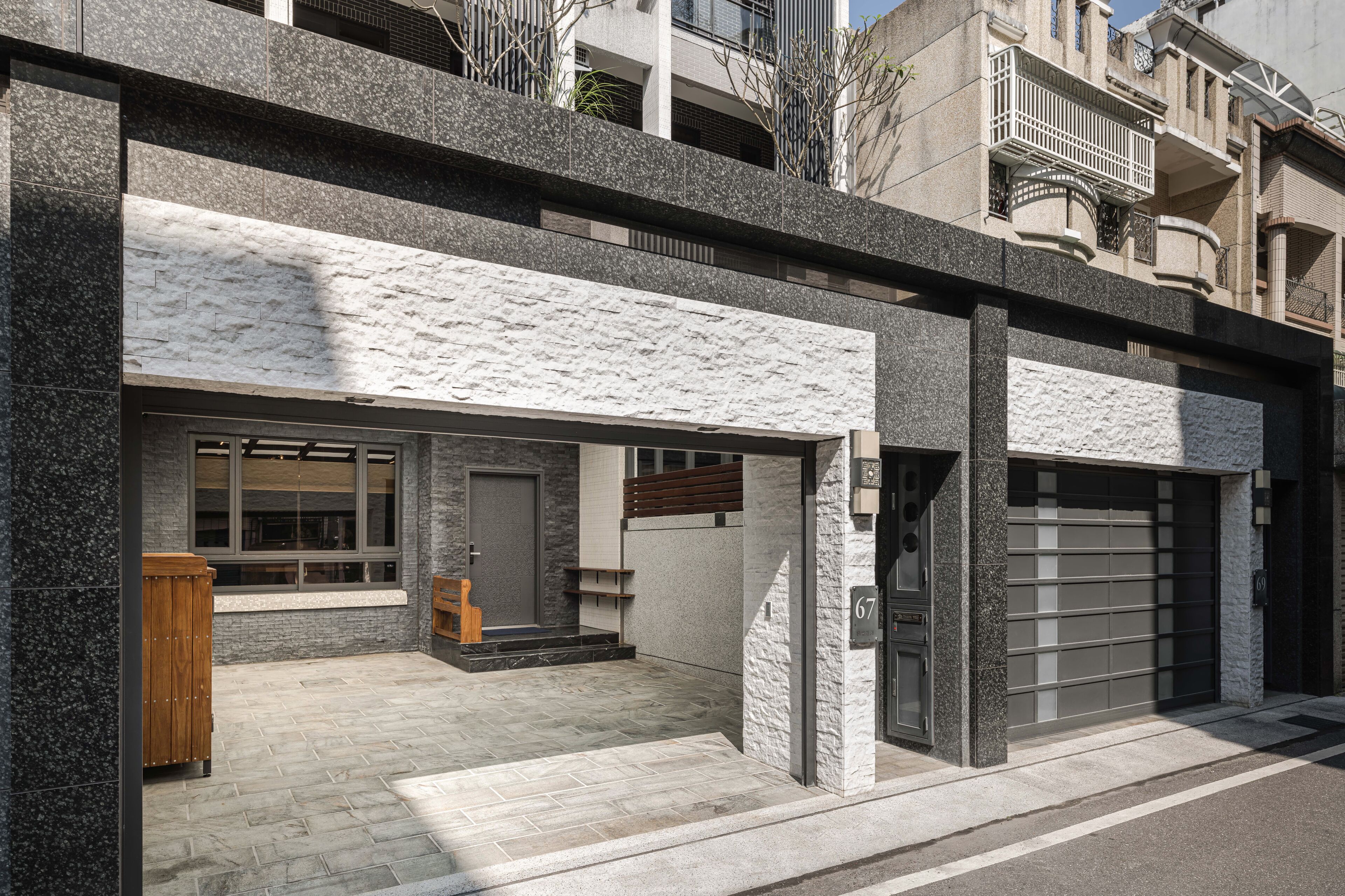 A modern building with a stone facade, large windows, and a garage door.