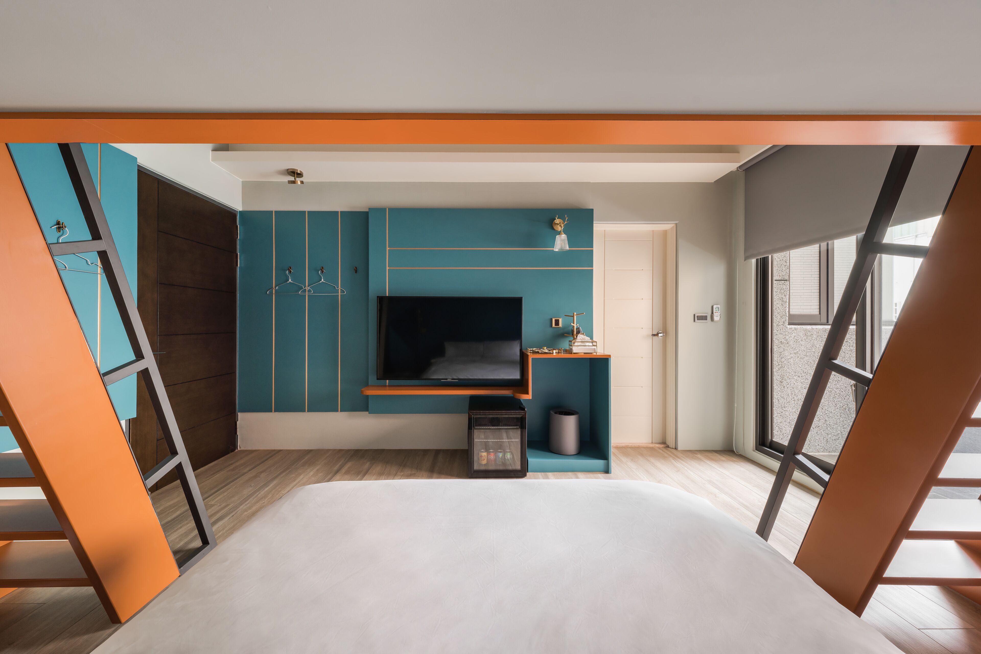 A modern bedroom with a bed, a TV, and a small desk area.