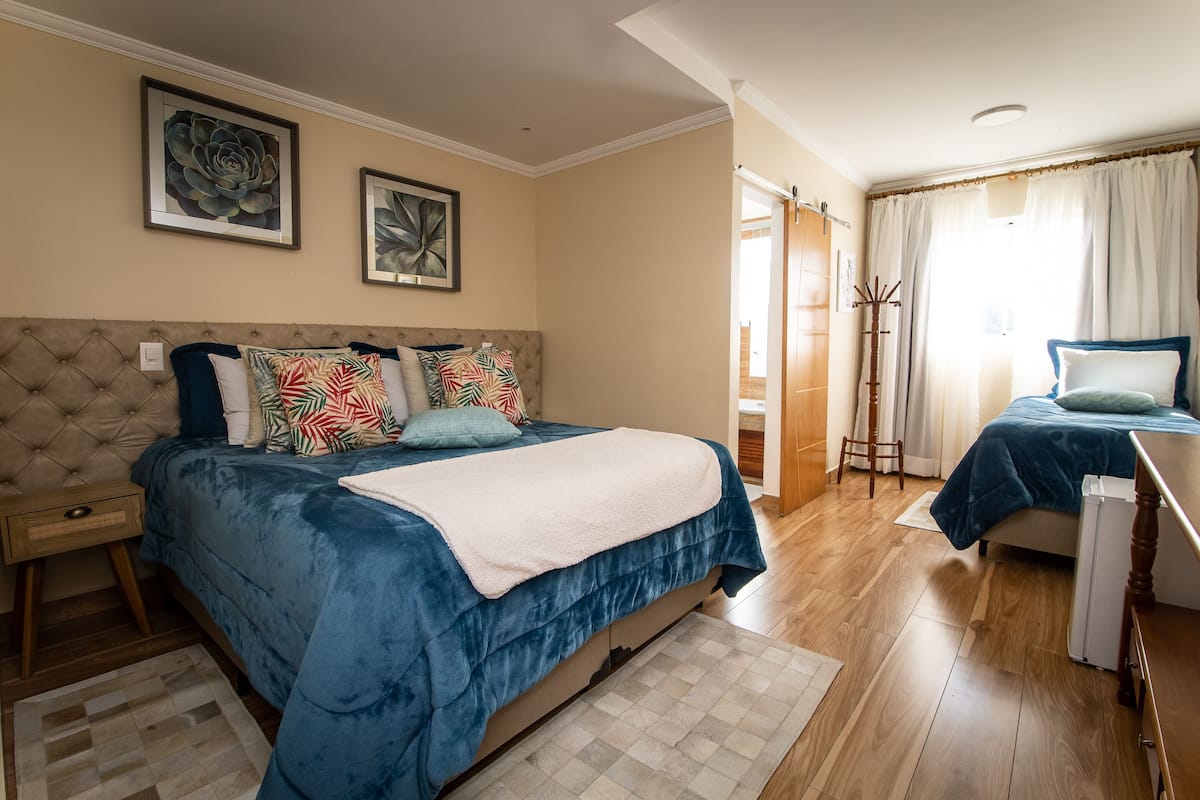 Une chambre avec un grand lit, une table de chevet, un porte-manteau et un plancher en bois.