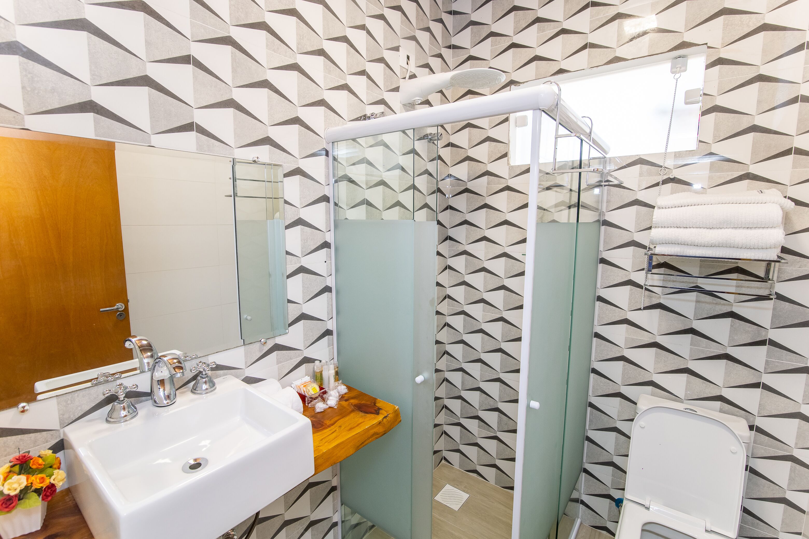 A bathroom with a sink, mirror, shower, and toilet.