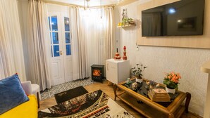 Uma sala de estar com sofá, mesa de centro, TV na parede e lareira.